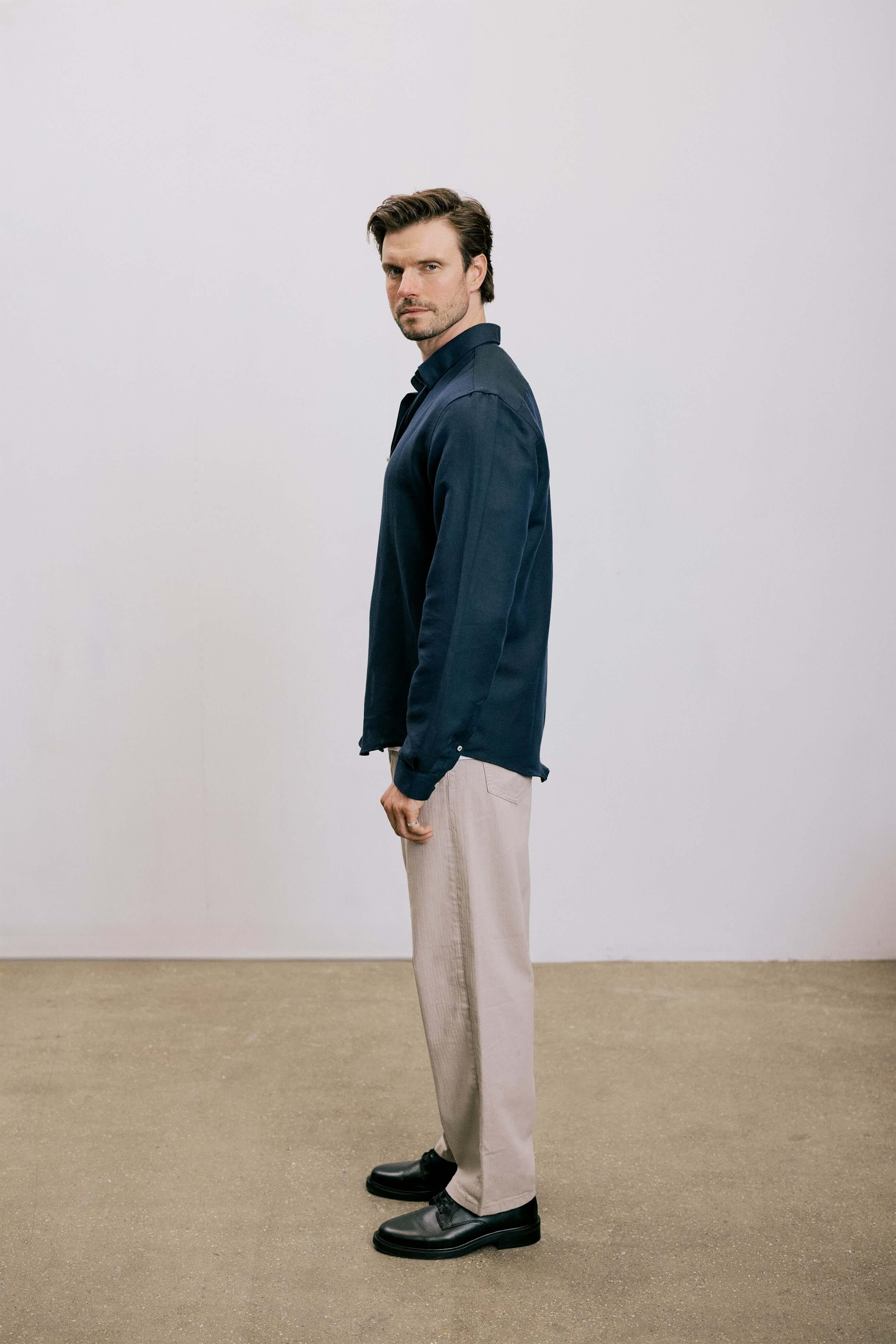 Side view of a man in VARRO Evelyn Mist Blue shirt with relaxed fit, hidden button-down collar, paired with beige pants.