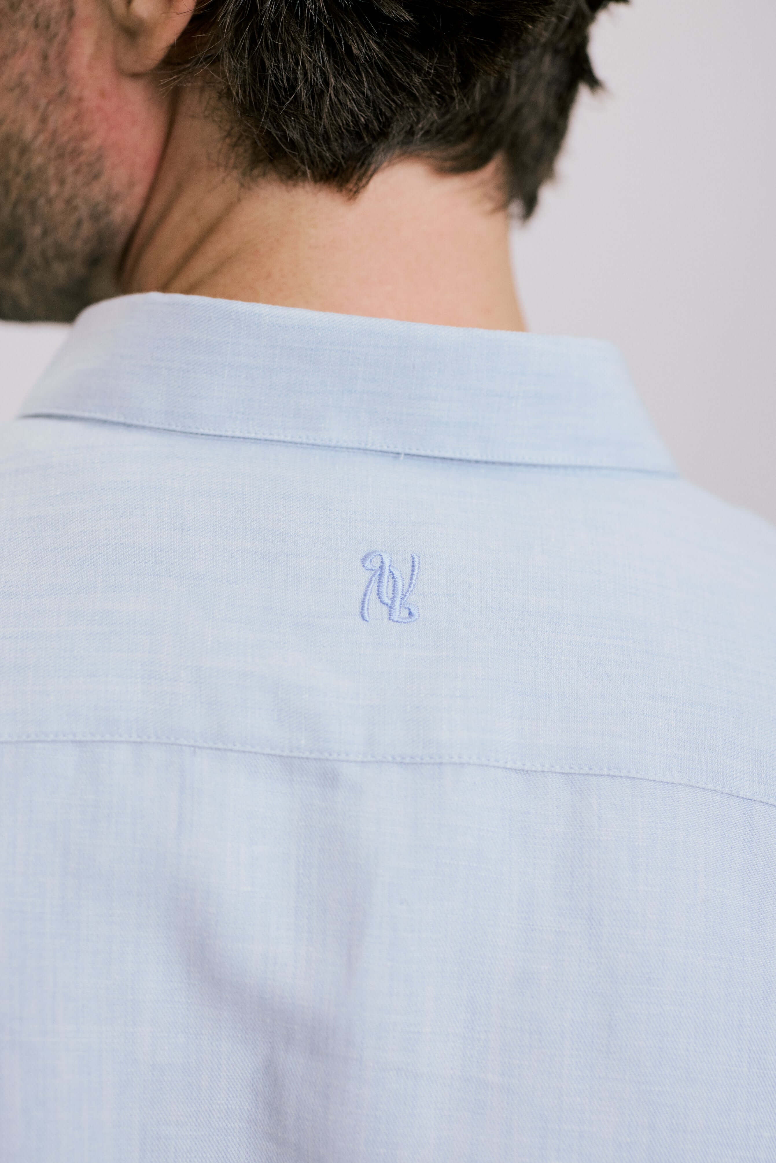 Back view of a man wearing VARRO Evelyn Mist Blue shirt, showcasing the hidden button-down collar and embroidery detail.