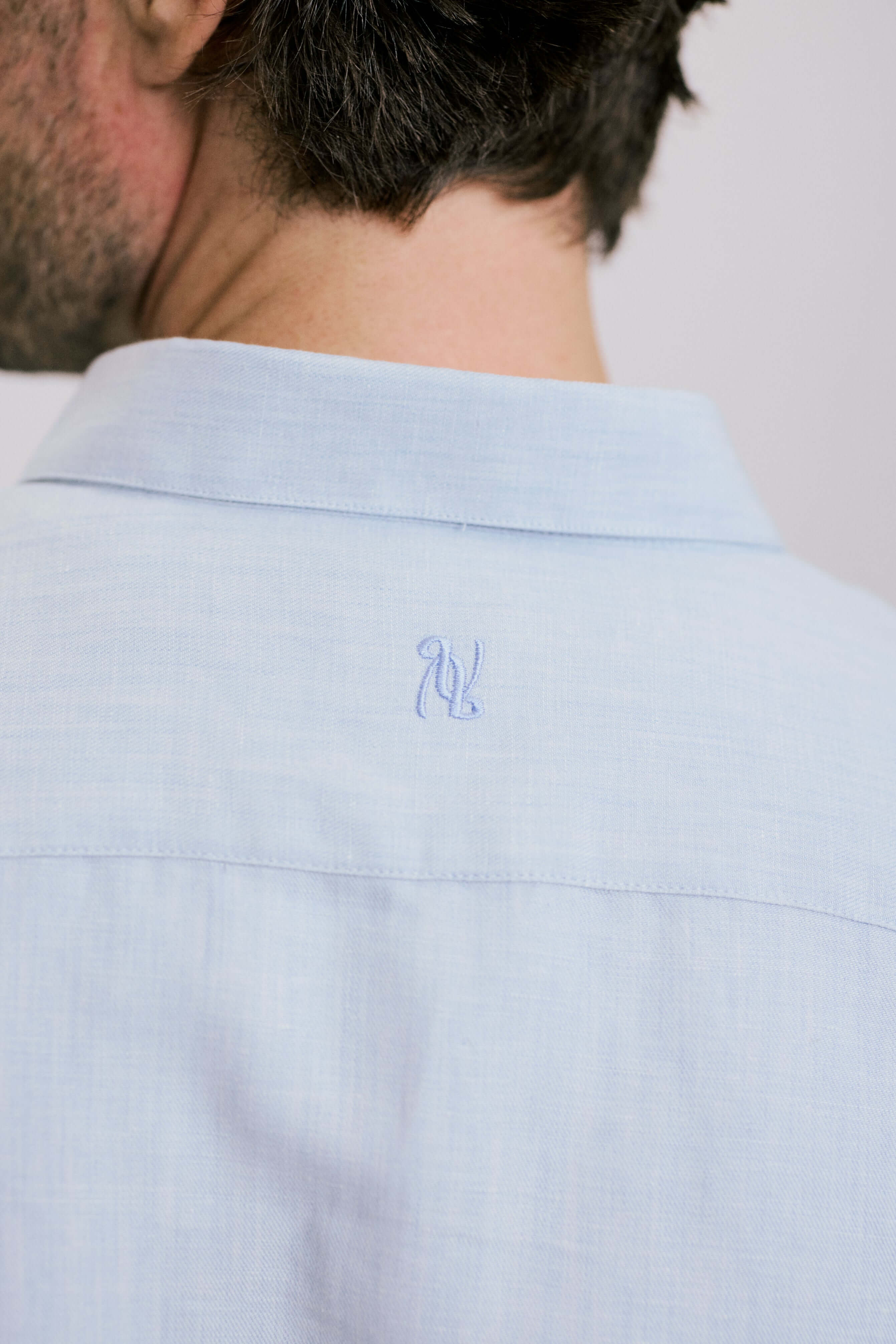 Back view of a man wearing VARRO Evelyn Mist Blue shirt, showcasing the hidden button-down collar and embroidery detail.