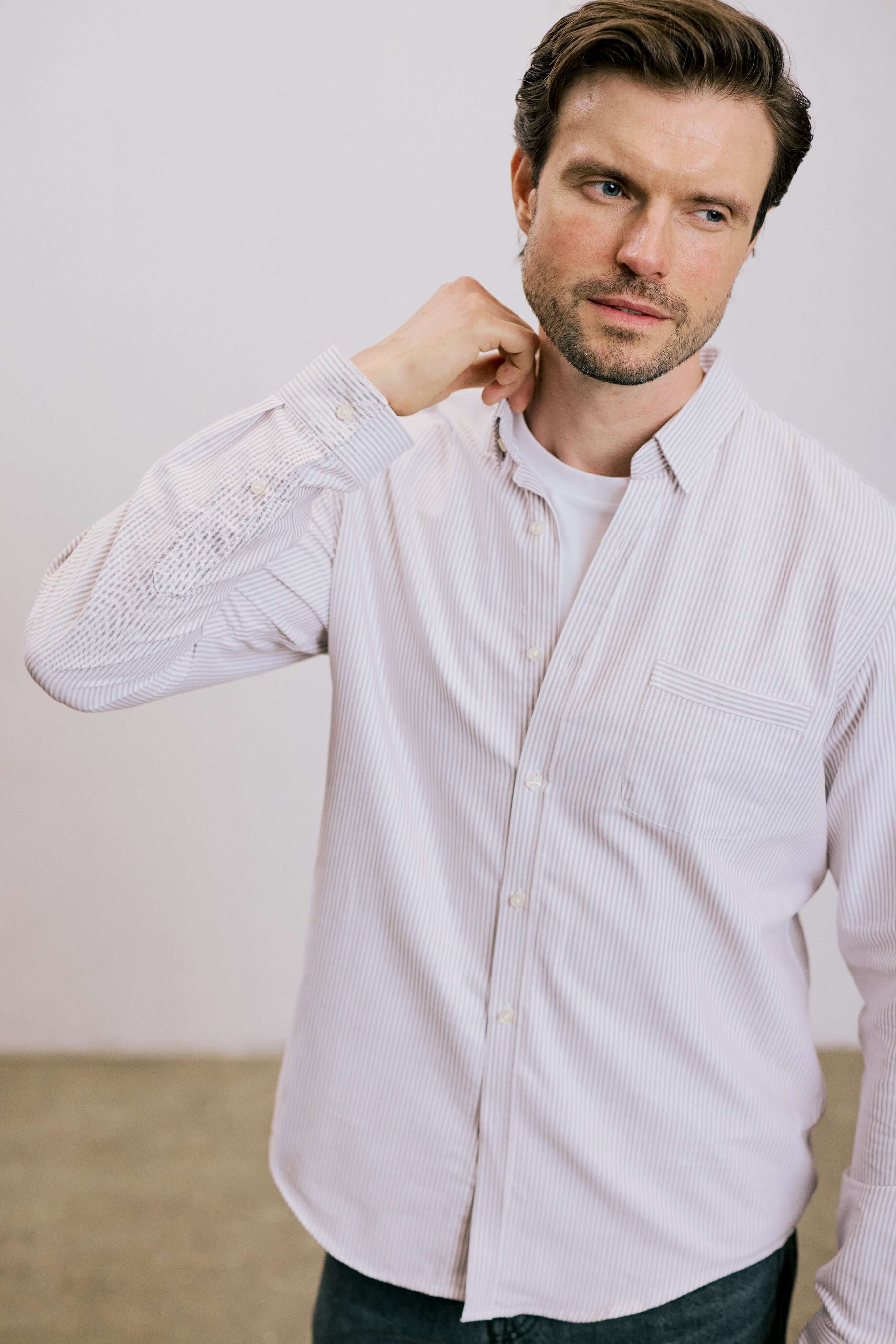 VARRO Keble Blue Stripe Oxford Shirt — model adjusting hidden button-down collar, showcasing relaxed fit and premium cotton.