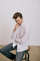 VARRO Keble Blue Stripe Oxford Shirt — Man seated, long sleeves folded, subtle details, relaxed fit, premium cotton fabric.