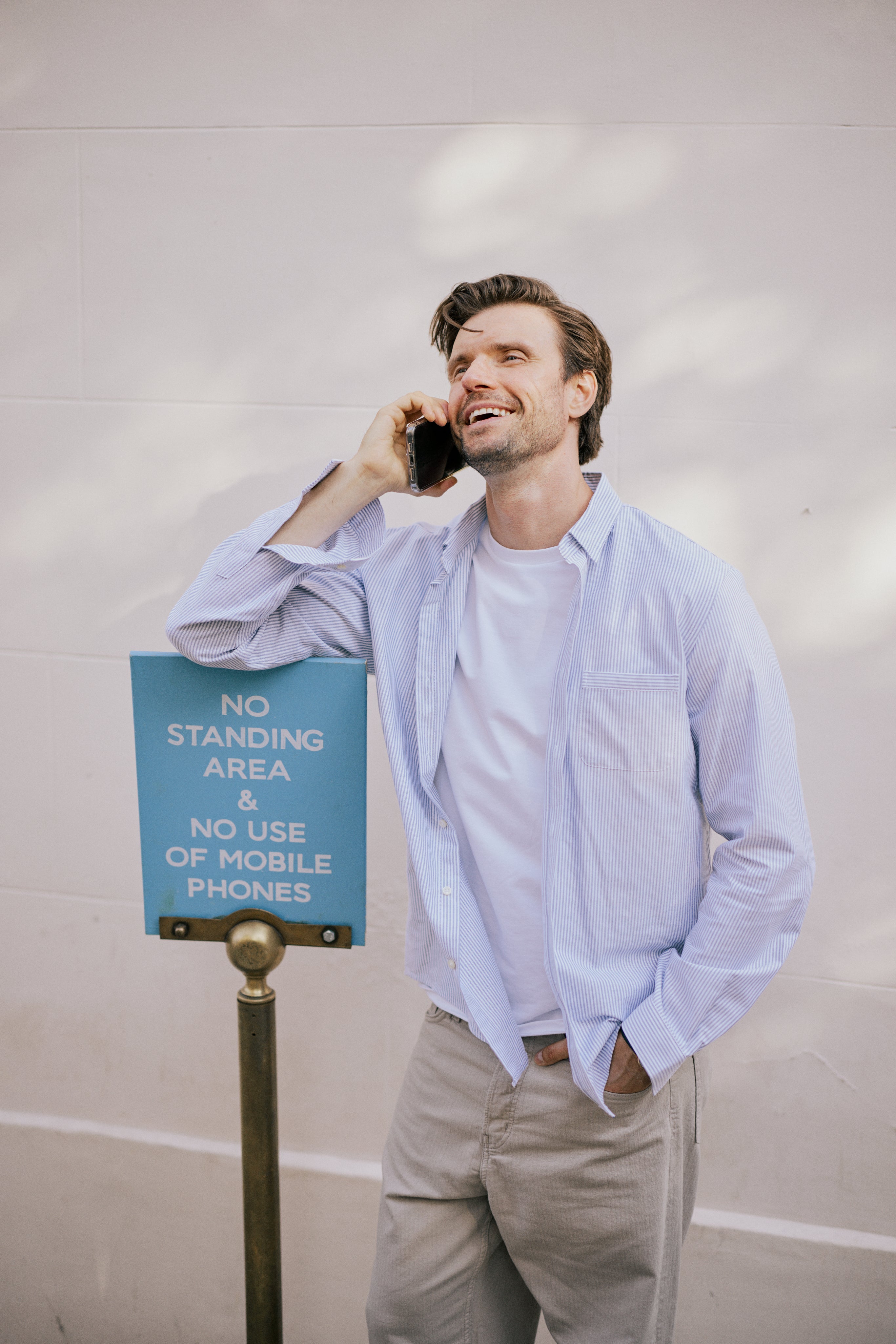 VARRO Keble Navy Stripe Oxford Shirt — model in relaxed fit, talking on phone, standing beside sign, long sleeves visible.